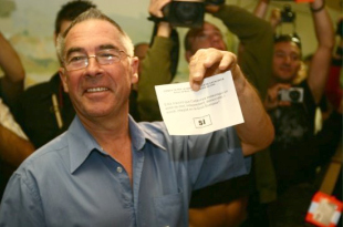 O primeiro votante do d&iacute;a amosa a s&uacute;a papeleta, a prol do Si